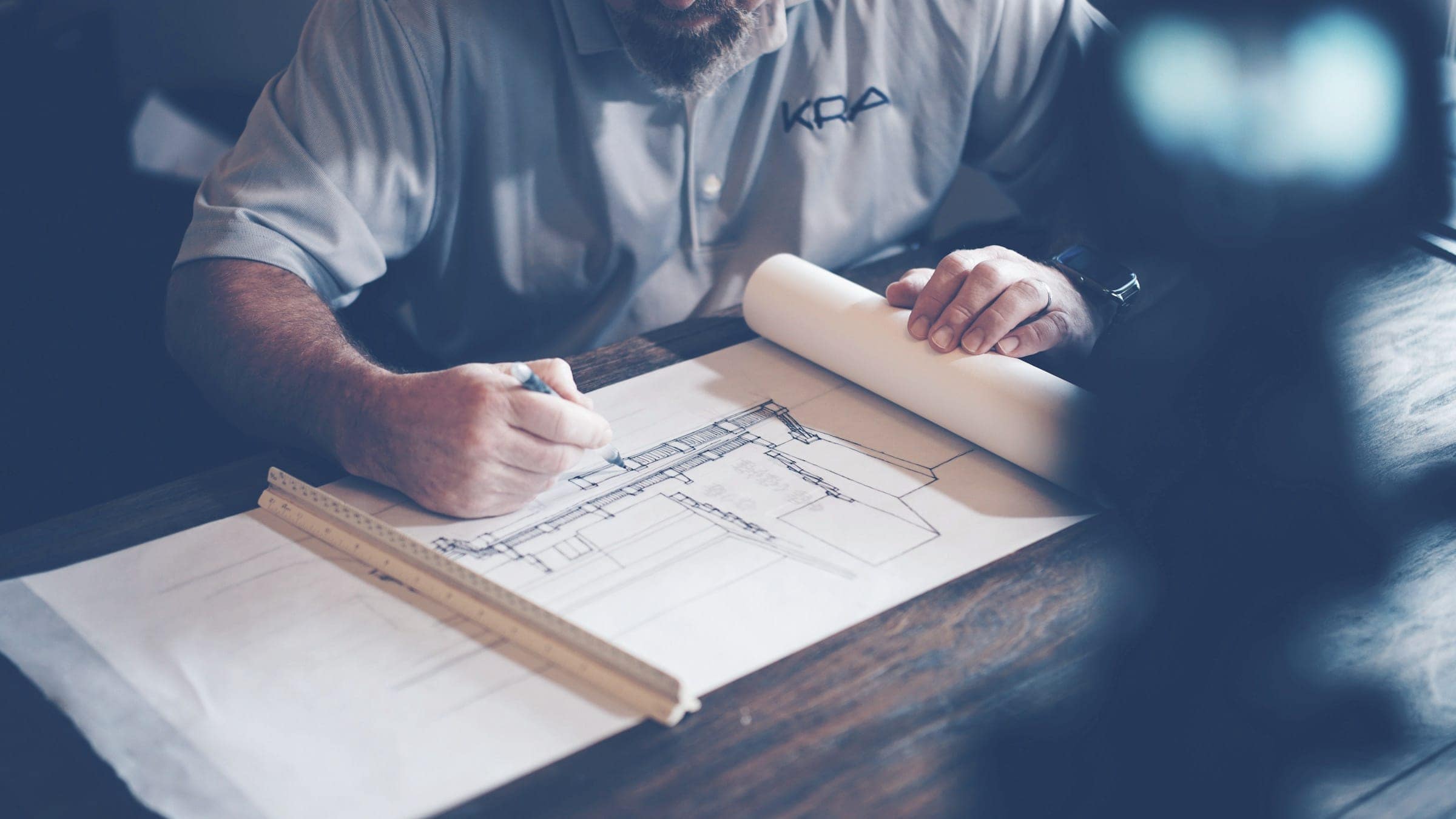 A person drawing on large architectural plans