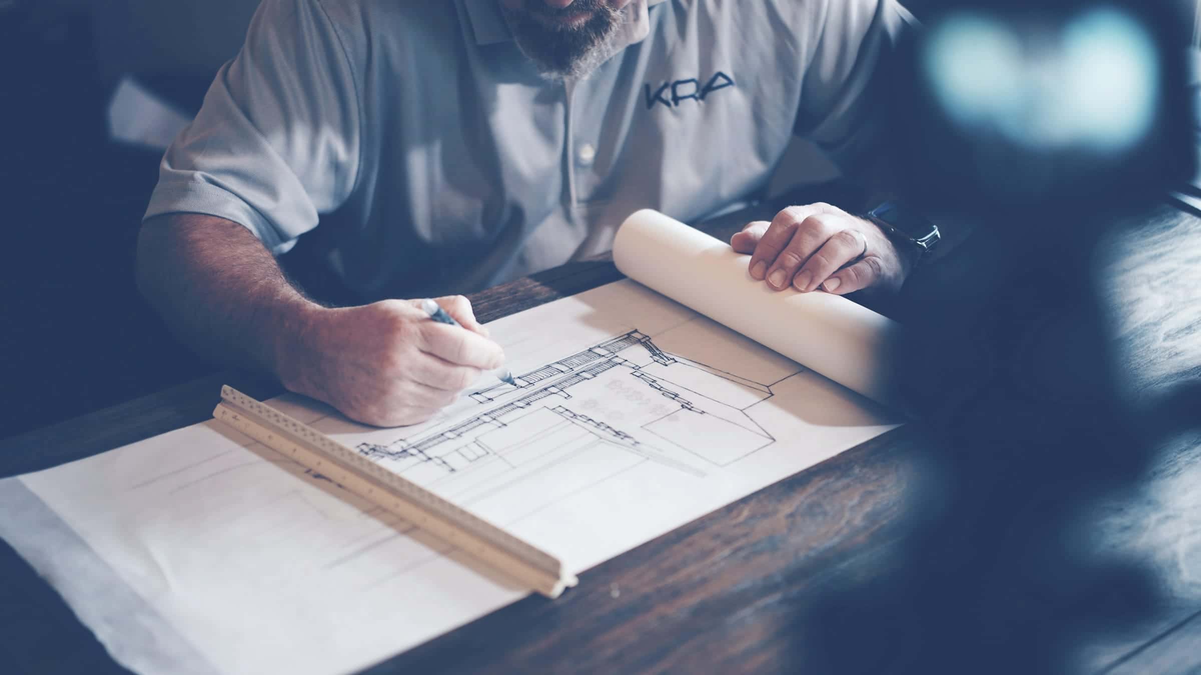 A person drawing on large architectural plans