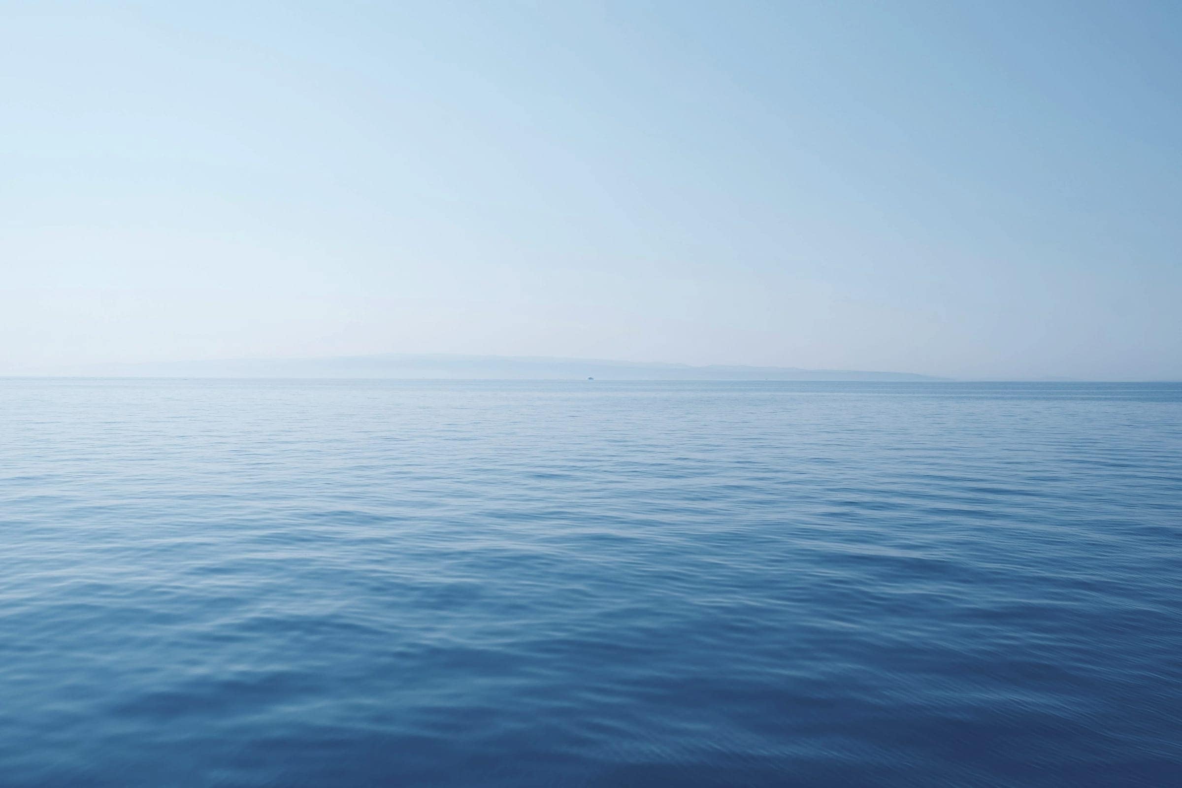 A calm blue sea meeting a clear horizon